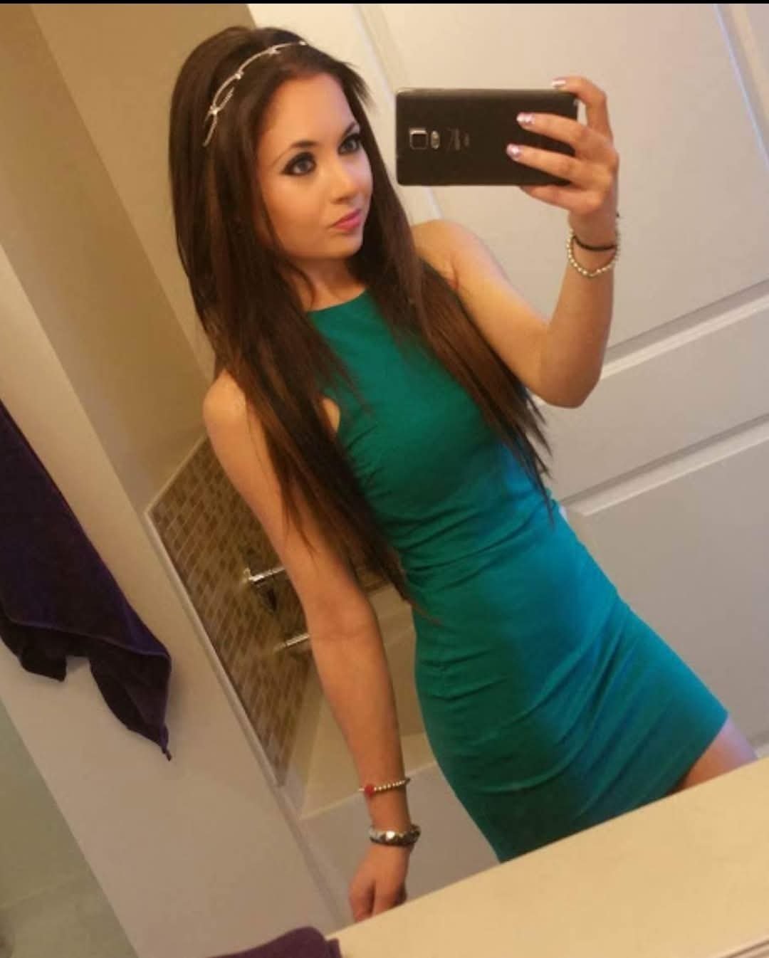 Jennifer Jorgensen Ahmed in a teal green dress with a silver headband taking a mirror selfie