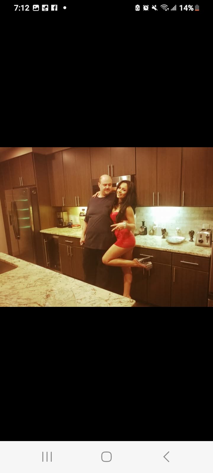 Jennifer Jorgensen Ahmed in a red romper posing with a companion in a kitchen