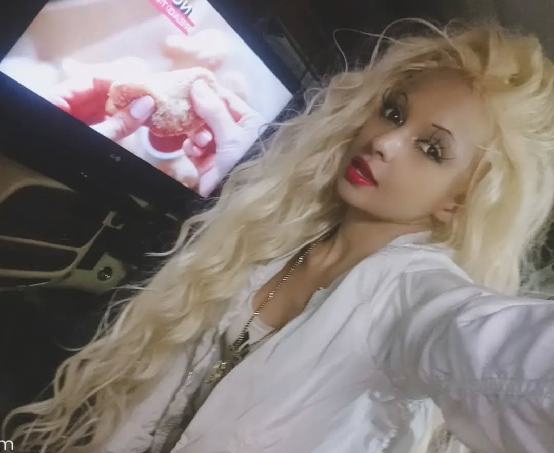 Jennifer Jorgensen Ahmed with long wavy blonde hair and red lipstick in a white blouse